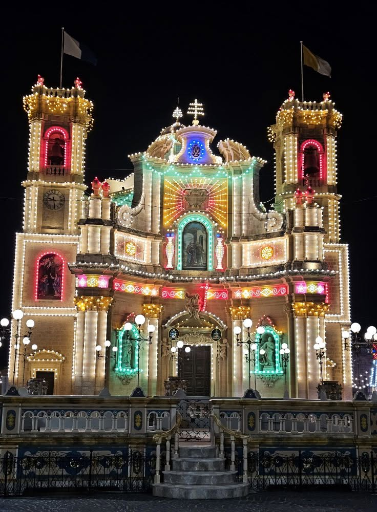 Illuminated church facade in Gharb at night during festa celebrations